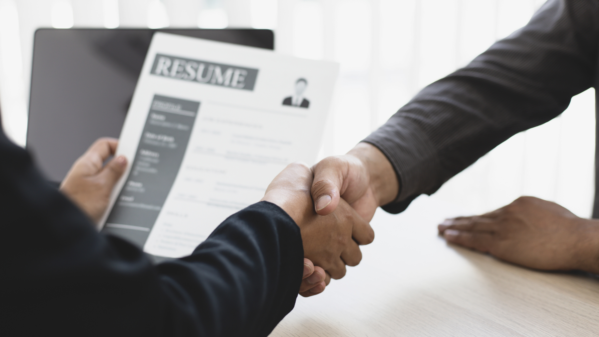 Employer Interviewing Job Applicant shaking hands looking at resume