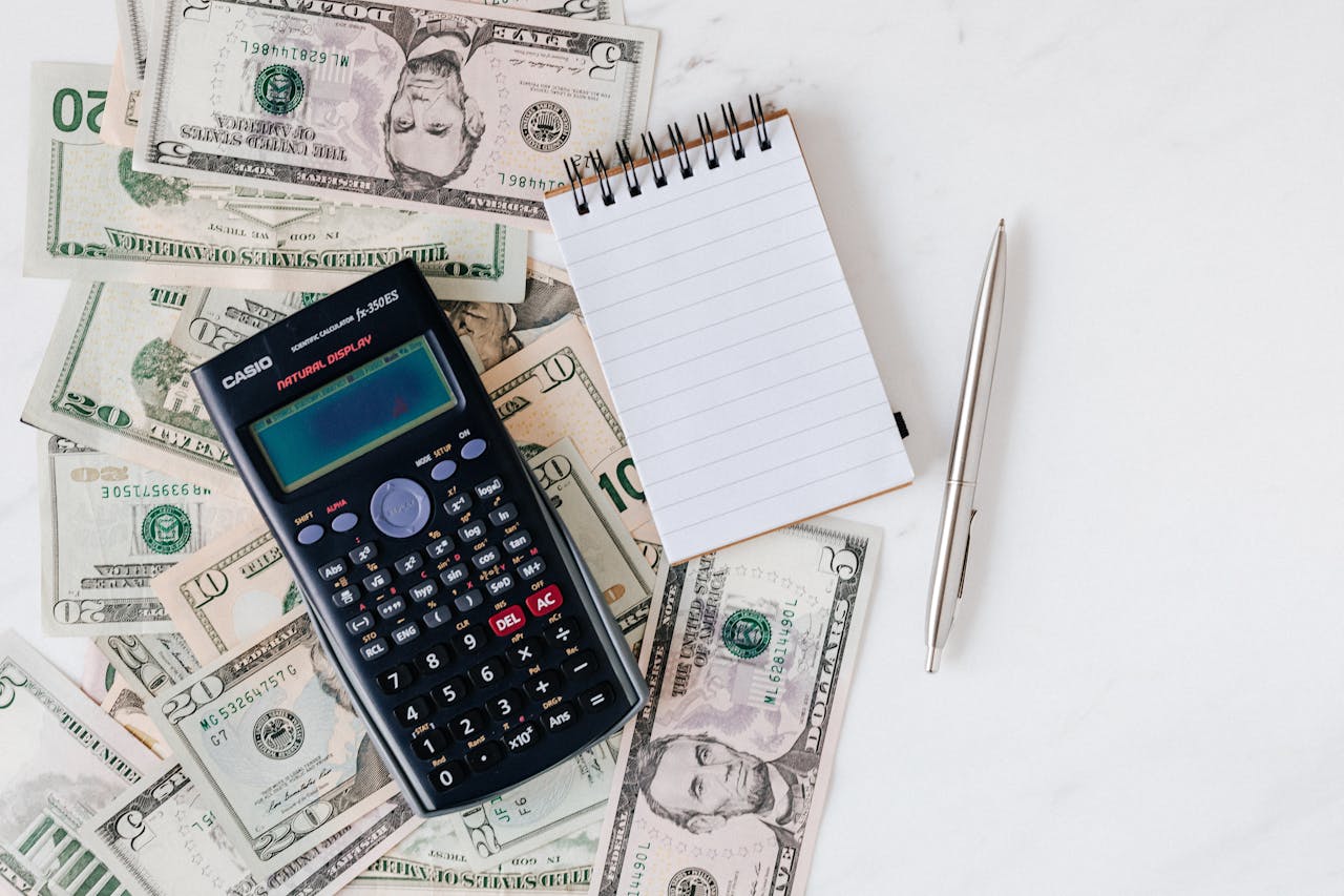 Loose cash with a notebook and calculator on top